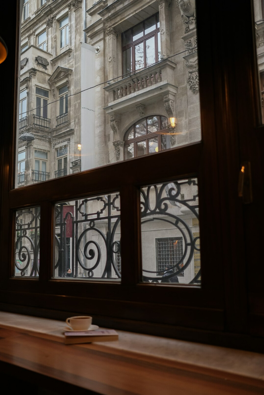 Laptop and coffee cup on a table near a city window