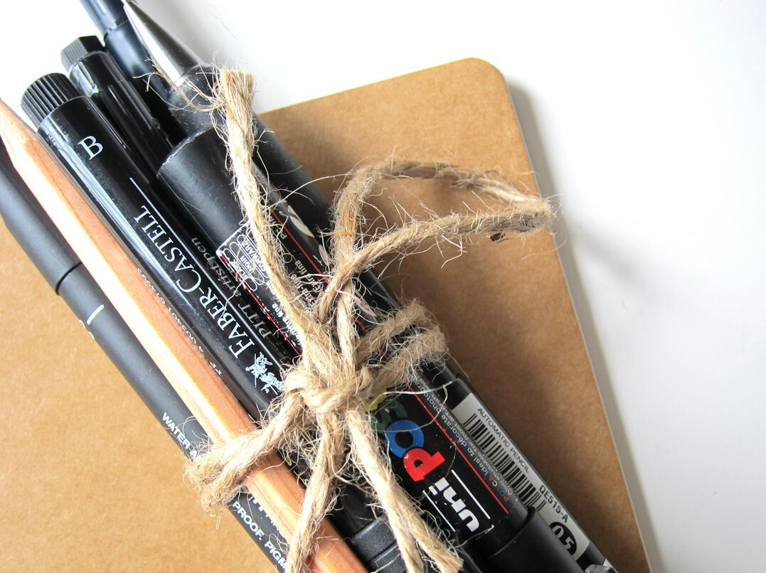 Stack of books and notebook with a pen on a desk