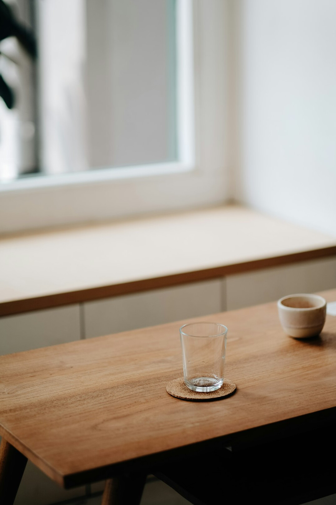 Minimalist desk with plant and cup of tea near a window